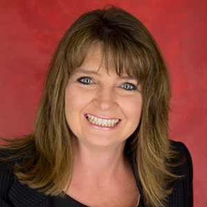 Smiling woman with shoulder-length brown hair against a red background.