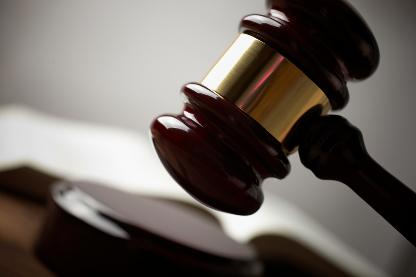 Close-up of a wooden judge's gavel with a blurred book in the background.